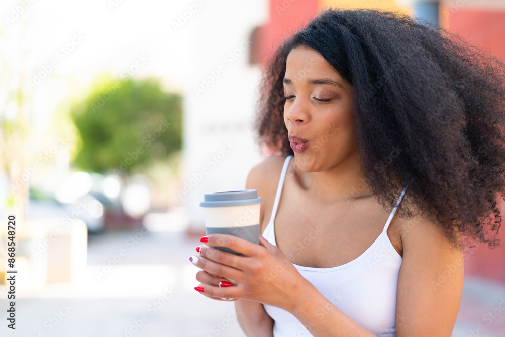 Young African American woman at outdoors holding a take away coffee Young African American woman at outdoors holding a take away coffee