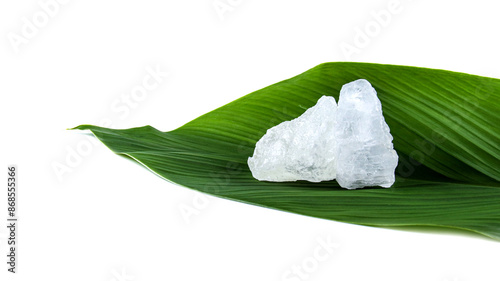 White crystal clear alum cube on green leaf isolated on white background.