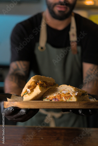 Chef Presenting a Delicious Sandwich on a Wooden Tray