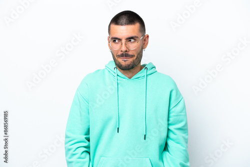 Young caucasian man isolated on white background having doubts while looking up photo