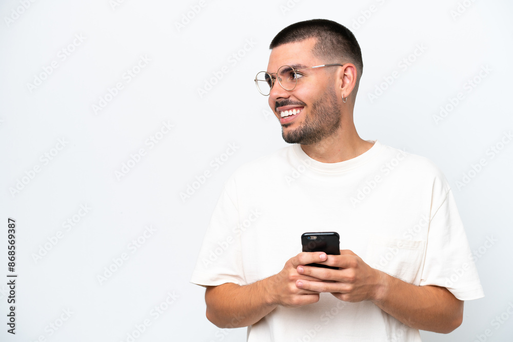 Young caucasian man isolated on white background using mobile phone and looking up Young caucasian man isolated on white background using mobile phone and looking up