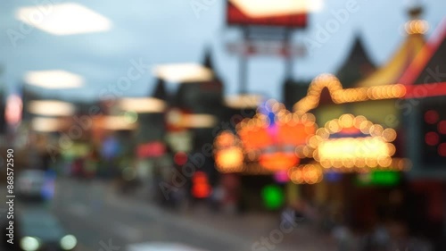 Colorful neon lights are shining from storefronts, tourists and cars are passing by on Clifton Hill, Niagara Falls, Ontario, Canada