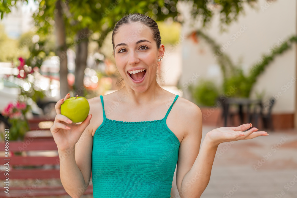 Young pretty woman with an apple at outdoors with shocked facial expression Young pretty woman with an apple at outdoors with shocked facial expression