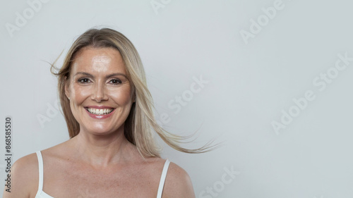 Nice cheerful healthy blonde mid adult mature woman looking at camera on white background. Mature lady portrait. Healthy face, skin care beauty, middle age skincare cosmetic and cosmetology concept