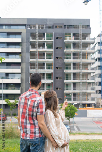 Pregnant young couple embrace looking at their future new home. planning the future in their apartment under construction. Real estate concept, new home purchase, rising prices.