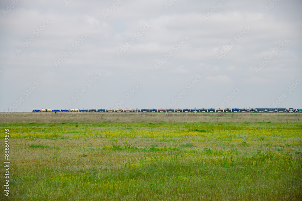 Fototapeta premium Locomotive pulls a very large and heavy freight train with wagons and tank cars along a railway