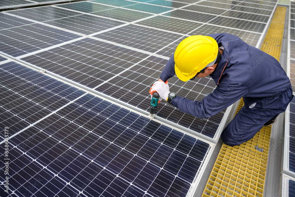A solar power system engineer installs, maintains, and inspects solar panels on the roof of a power plant using an electric drill. offering solar cell installation inspection services. A solar power system engineer installs, maintains, and inspects solar panels on the roof of a power plant using an electric drill. offering solar cell installation inspection services.