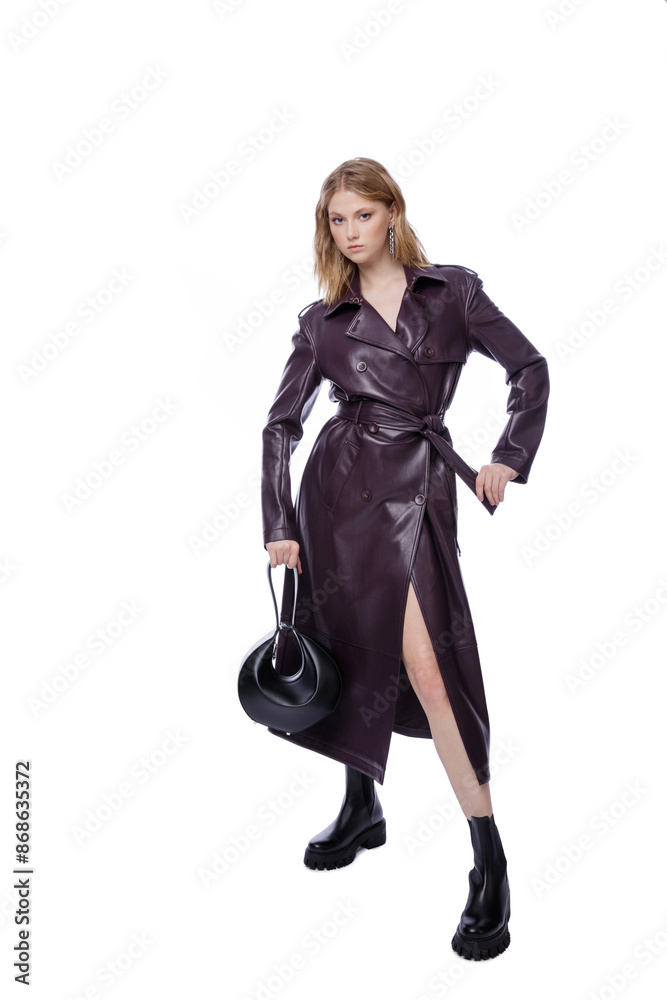 High fashion photo of a beautiful elegant young woman in pretty long purple lilac leather jacket, coat, handbag posing on white background. Slim figure. Blonde High fashion photo of a beautiful elegant young woman in pretty long purple lilac leather jacket, coat, handbag posing on white background. Slim figure. Blonde