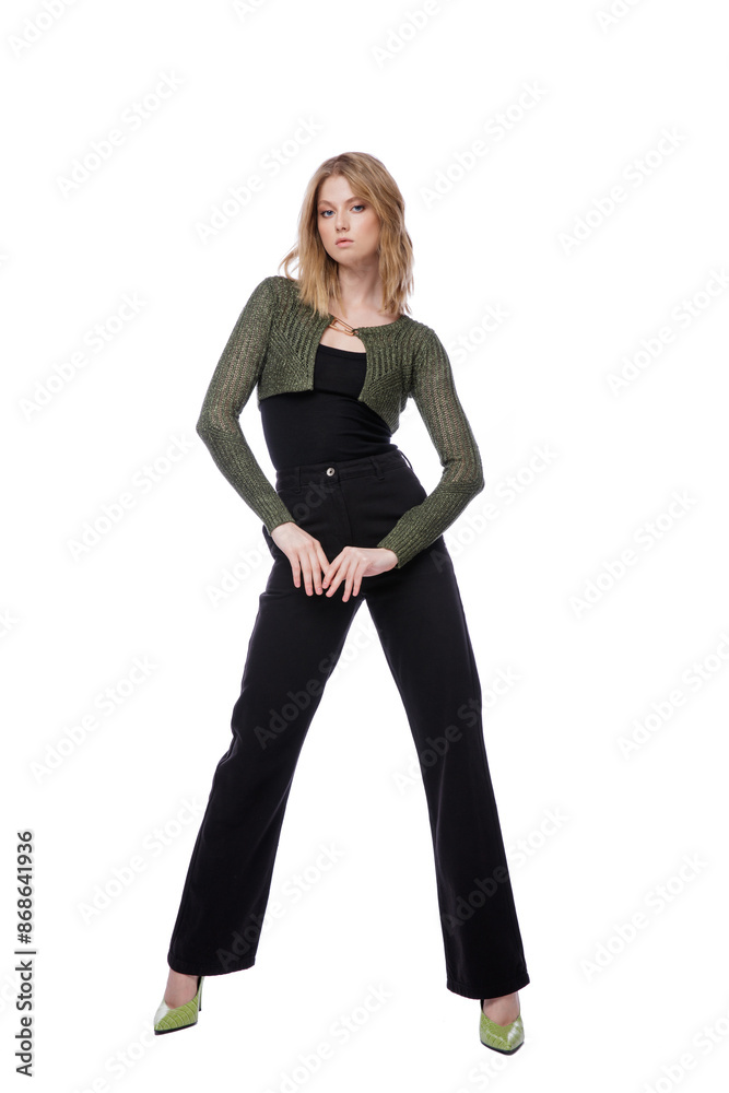 High fashion photo of a beautiful elegant young woman in pretty black denim pants, trousers, top, green short jacket posing on white background. Slim figure. Blonde