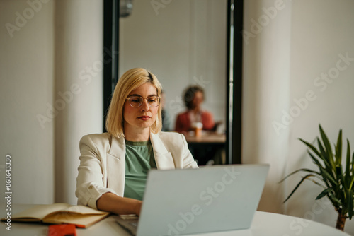 A woman having an online business meeting and using a laptop while sitting in an office