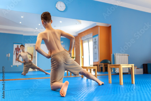 The boy is doing kinesotherapy exercises alone. Exercises for correcting the spine and pelvis, scoliosis. photo