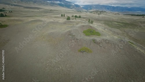 The copter flies high in the mountains over hills, rivers and forests. Cloudy weather, evening.