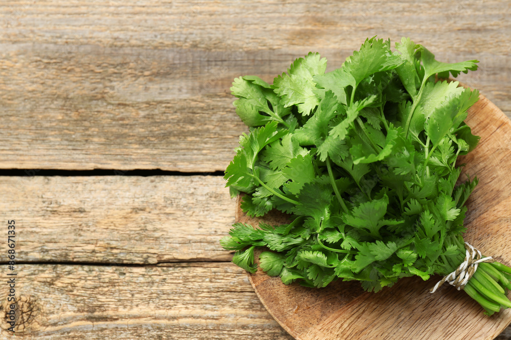 Bunch of fresh coriander on wooden table, top view. Space for text Bunch of fresh coriander on wooden table, top view. Space for text