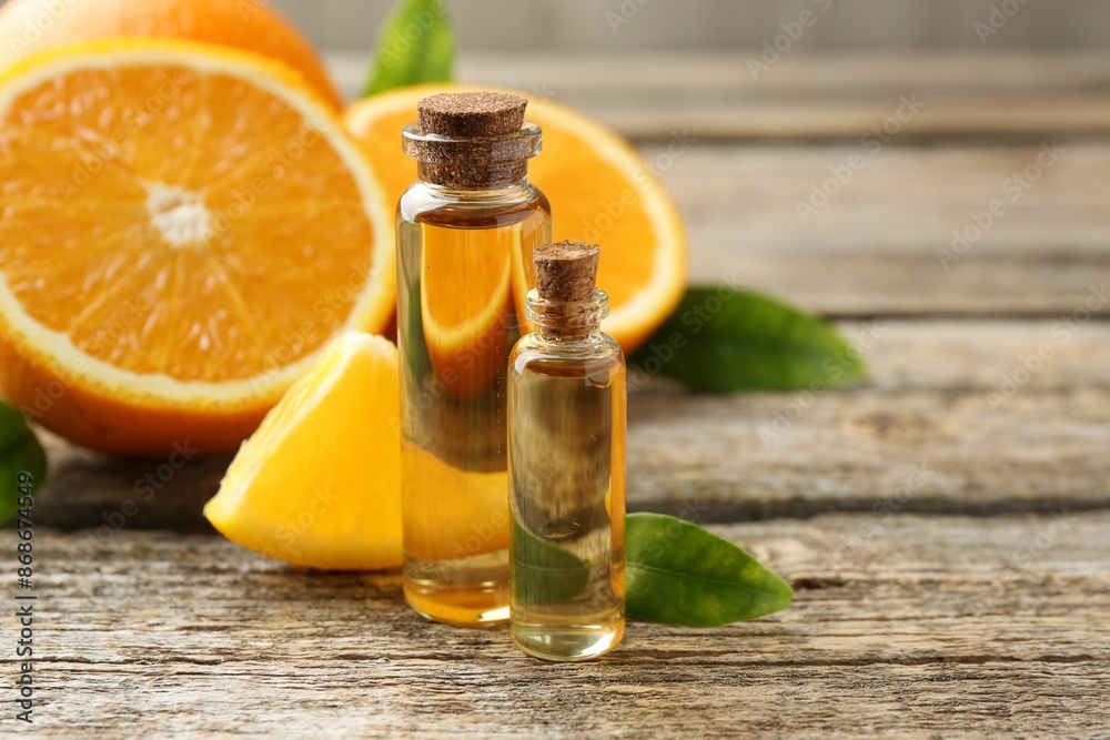Essential oils in bottles, oranges and green leaves on wooden table Essential oils in bottles, oranges and green leaves on wooden table