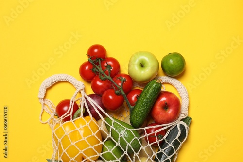 Fototapeta Naklejka Na Ścianę i Meble -  Delivery of vegetarian products. String bag with different vegetables and fruits on yellow background, top view