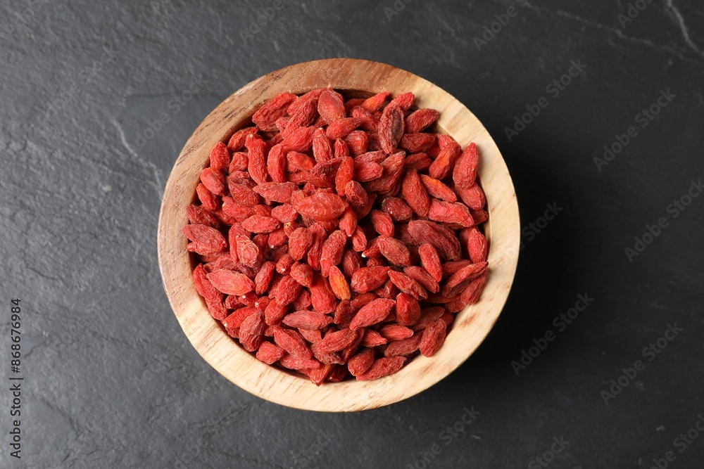 Dried goji berries in bowl on dark textured table, top view Dried goji berries in bowl on dark textured table, top view