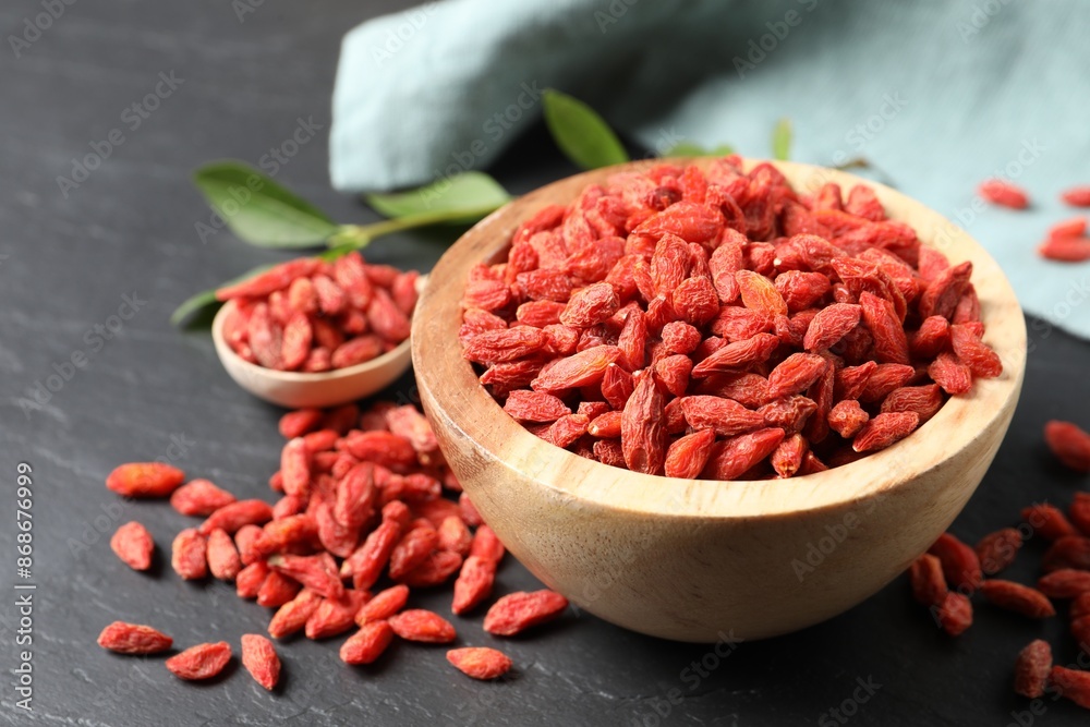 Dried goji berries in bowl on dark textured table, closeup Dried goji berries in bowl on dark textured table, closeup