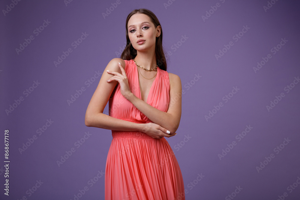 High fashion photo of a beautiful elegant young woman in pretty long coral red dress posing on purple, lilac background. Slim figure. High fashion photo of a beautiful elegant young woman in pretty long coral red dress posing on purple, lilac background. Slim figure.