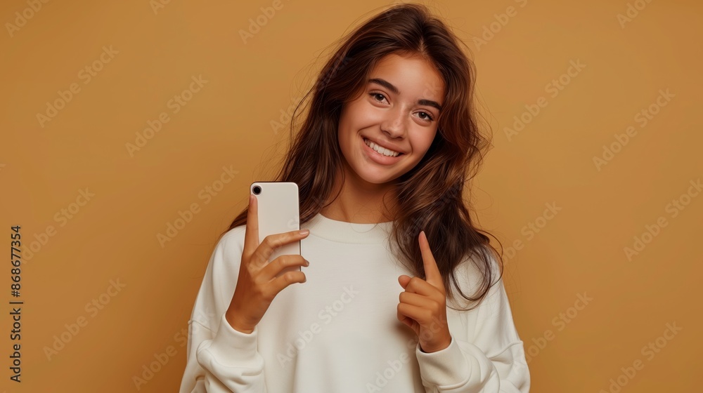 Attractive smiling girl with phone and raising finger up, smm marketing post app isolated on biege background Attractive smiling girl with phone and raising finger up, smm marketing post app isolated on biege background