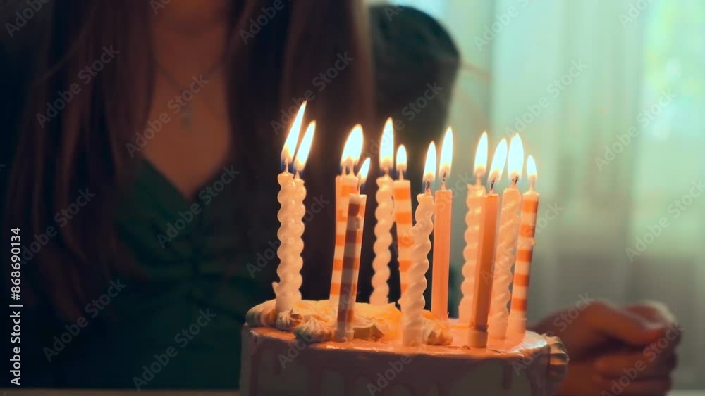 A young teenage girl blowing out candles on a cake in the dark, birthday