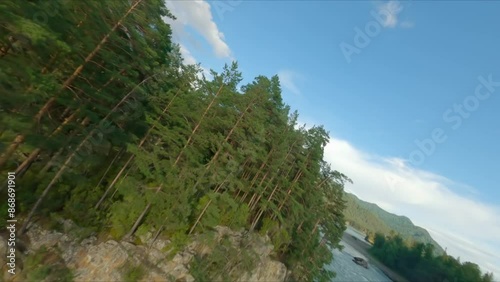 FPV sports drone extreme flight high cliff rocky texture over speed movement natural mountain river water flow narrow gorge. Aerial view nature cascade stream canyon with spruce forest evergreen trees