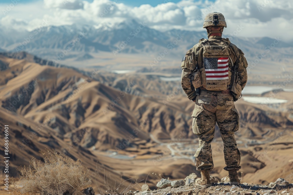 Portrait of American Soldier with Flag on Back, Standing in Desert Landscape on Sunny Day, Shot from Behind
