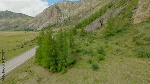 The FPV copter flies at high speed close to the rock rock. Excellent views of the mountain landscapes. Sunny weather, beautiful mountain landscapes, mountain river, green forest.