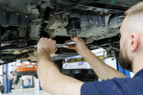 A mechanic replaces the fine filter for the transmission oil. Car on a lift in a car service center