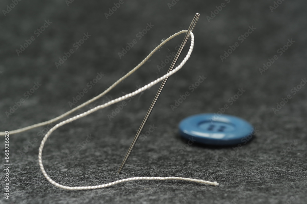 Needle with thread on grey background Needle with thread on grey background