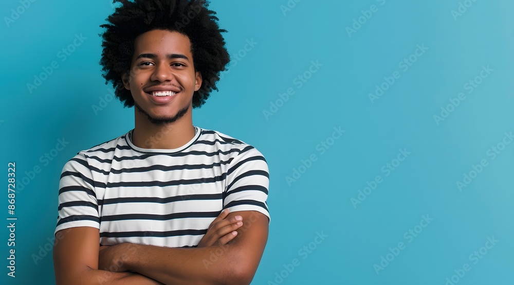 Fototapeta premium Young Man with Afro Smiling in Striped T-Shirt Against Blue Background