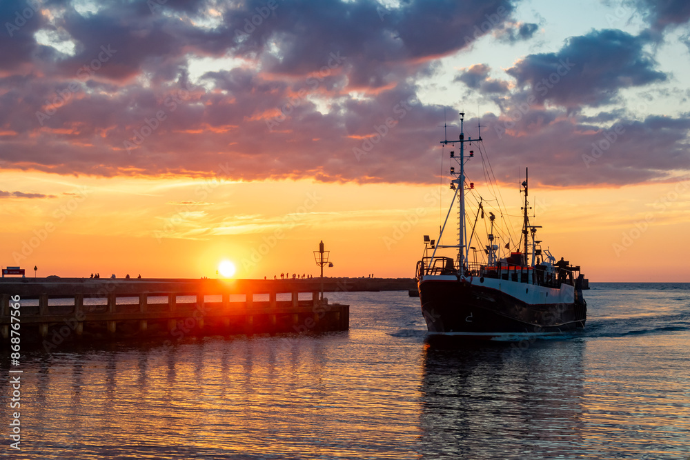 a ship entering the port of Ustka at sunset a ship entering the port of Ustka at sunset