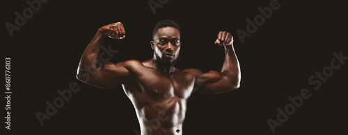 A shirtless, muscular man flexing his biceps against a black background.