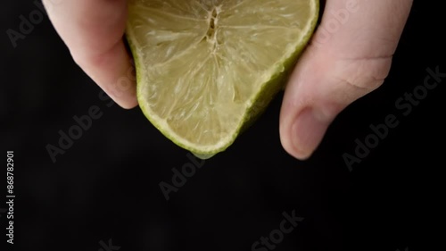 Squeezing green lime juice. Close Up on male hand extracting juice from a green lime half.