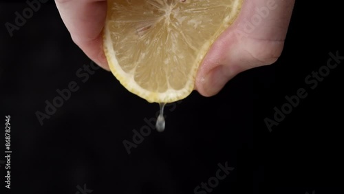 Squeezing lemon juice. Close Up on male hand extracting juice from lemon half.