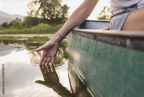 Quadro su tela Active young woman paddling a canoe on a lake surrounded by green summer nature, close up shot