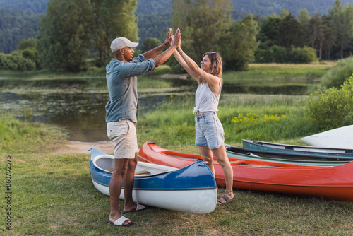 Happy young couple at canoe ride giving high five on a beautiful green lake photo