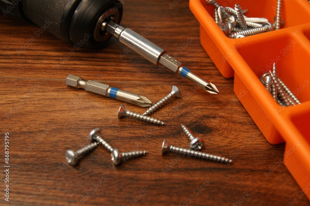 A box of screws and a screwdriver on a dark wooden table. A box of screws and a screwdriver on a dark wooden table.