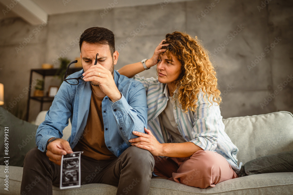 Stress couple sit and talk about ultrasound picture of unwanted baby Stress couple sit and talk about ultrasound picture of unwanted baby