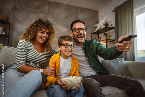 Family of three enjoy together watch movie and eat popcorn at home © Miljan Živković