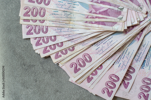 A thick stack of Turkish lira is laid out on a gray velvet table, ready to be counted, 200 Turkish lira bills, the currency for buying real estate,giving up cash and switching to non-cash payments photo