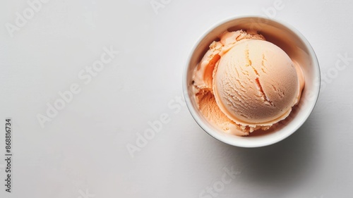 Single scoop of peach-colored ice cream in white bowl