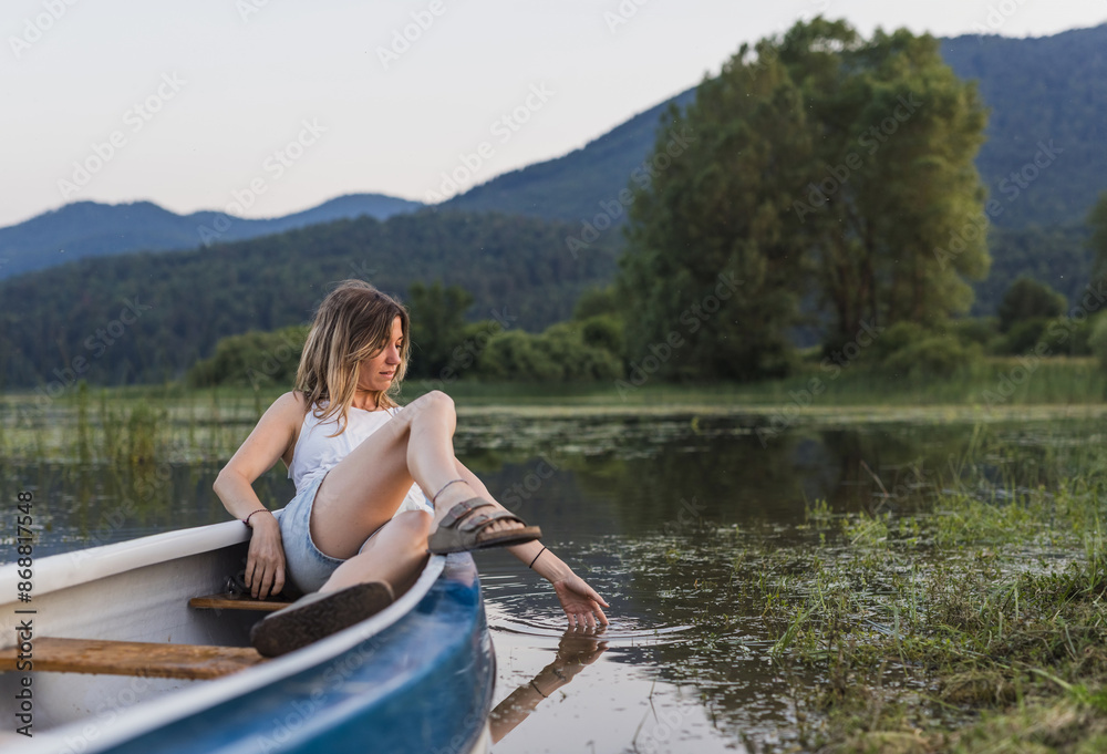 Portrait of a young woman relaxing in a canoe on a lake in nature Portrait of a young woman relaxing in a canoe on a lake in nature