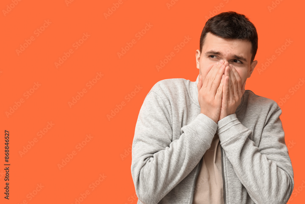 Handsome young man feeling bad smell on orange background Handsome young man feeling bad smell on orange background