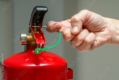 Fotografie Close up of a hand pulling the safety pin of a fire extinguisher