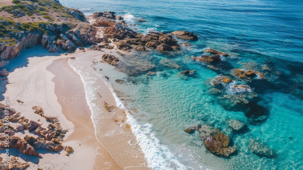 Obraz premium This image presents a coastal view from a high perspective where clear waters meet the rocky beach edge, capturing the pristine ocean and rugged shoreline beautifully.
