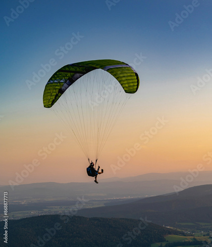Paragliding concept, a paraglider pilot fly in the sky on the nature mountain landscape background.