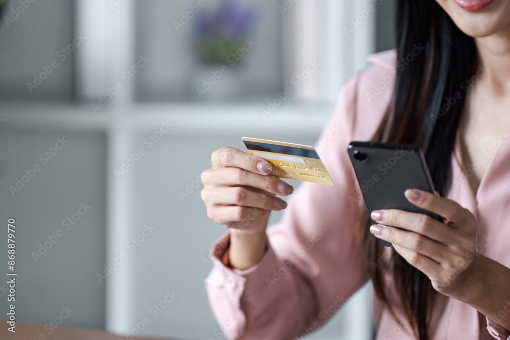 Woman Using Credit Card for Online Shopping on Smartphone in Modern Home Office Setting
