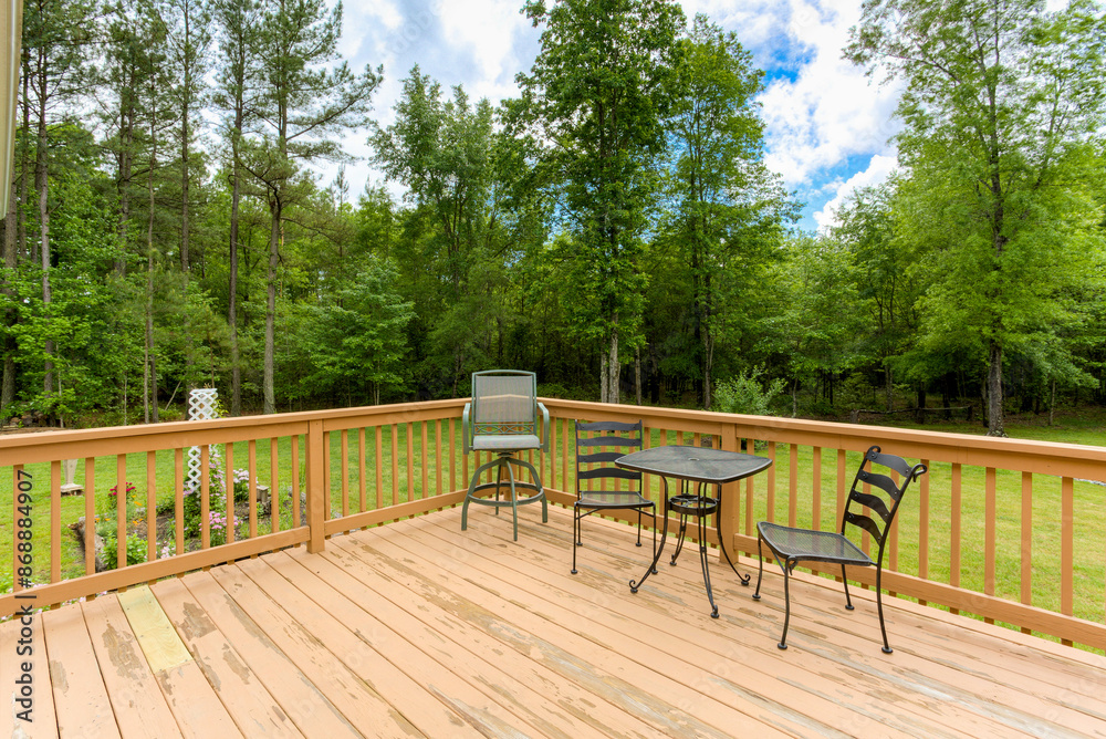 Outdoor Wooden Deck With Metal Chairs And Table Surrounded By Trees Outdoor Wooden Deck With Metal Chairs And Table Surrounded By Trees