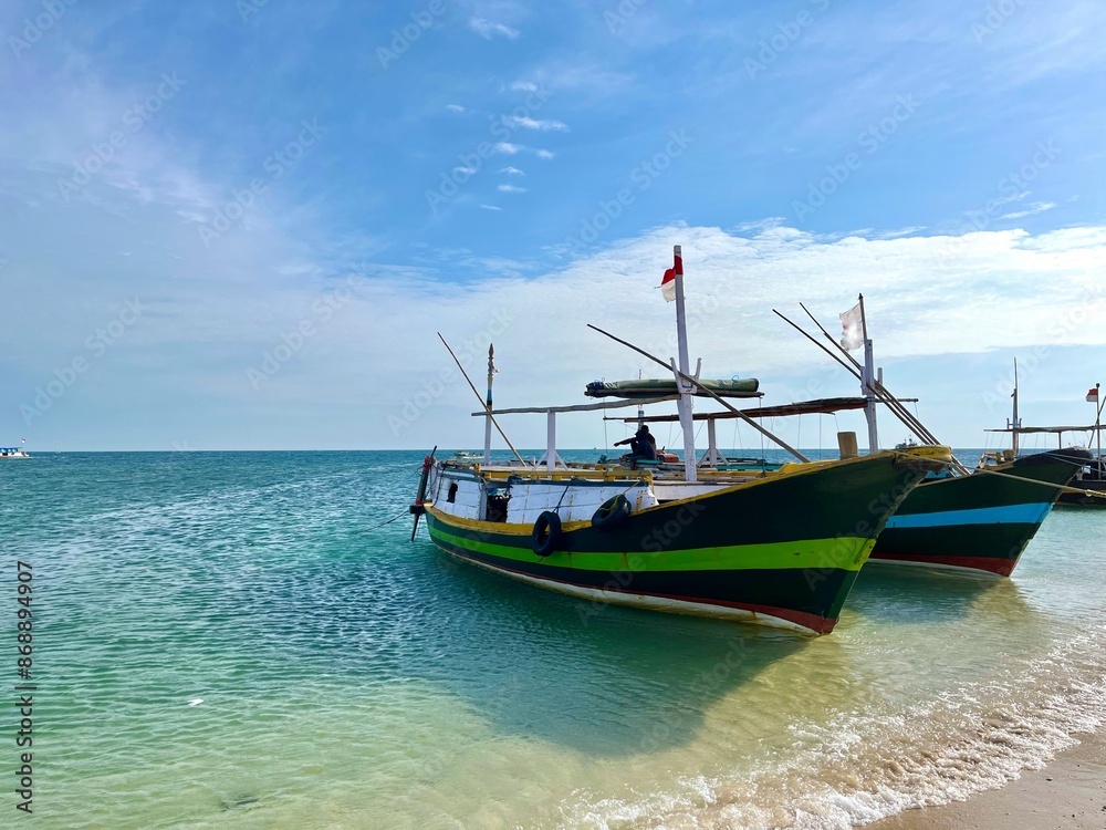 Fototapeta premium Several traditional wooden fishing and passenger boats moored on the beautiful beach in Gili Ketapang, Indonesia