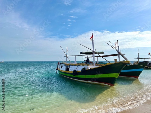 Several traditional wooden fishing and passenger boats moored on the beautiful beach in Gili Ketapang, Indonesia